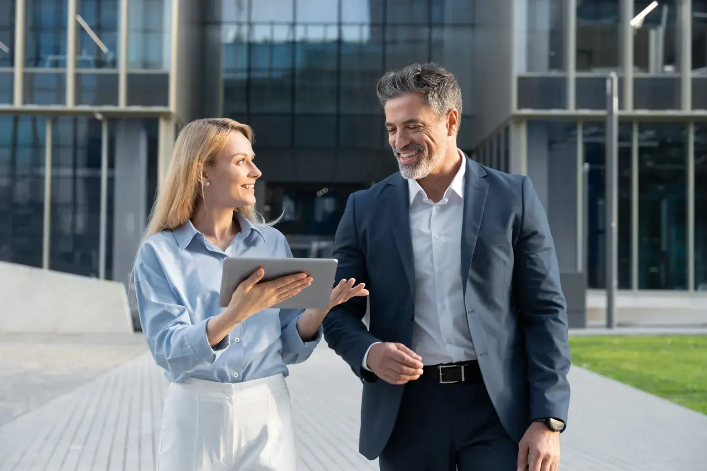 Two senior professionals reviewing work together outside a corporate building